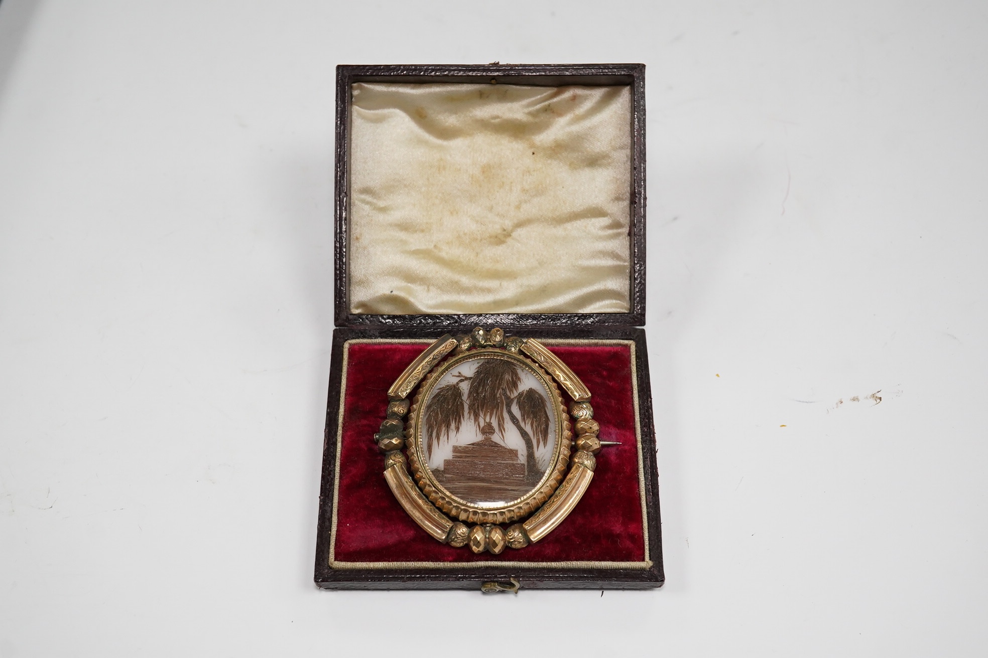 A cased Victorian yellow metal and plaited hair sey oval mourning brooch, 59mm. Condition - fair